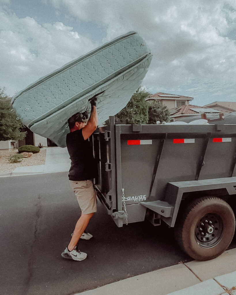 A mattress with no covers being lifted into a junk removal trailer in Phoenix Arizona